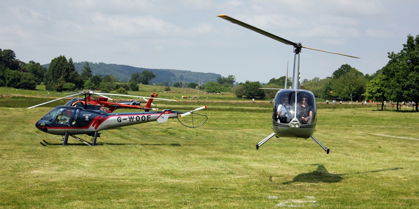 A picture of two helicopters landing on a helipad situated amidst lush greenery in Bali