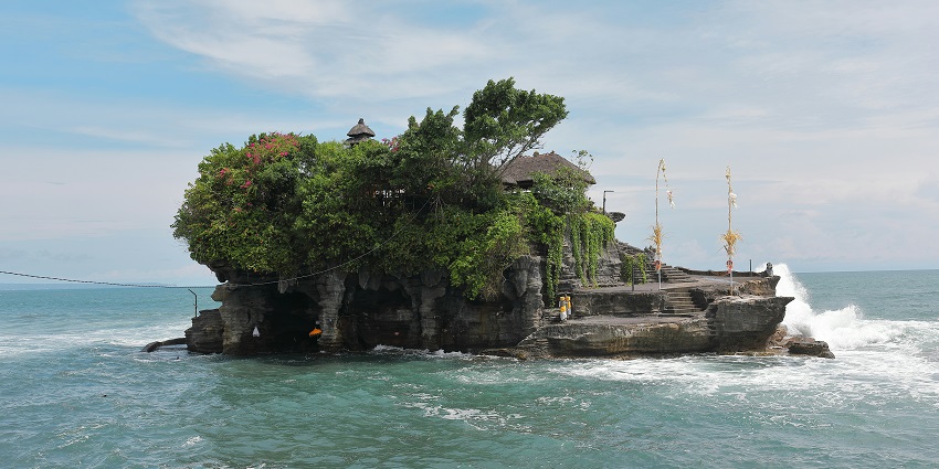 Sunset view of Tanah Lot temple on a rock formation in the middle of Ocean in Bali.