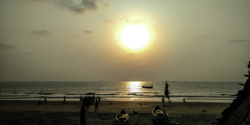 Sunset view at Tarkarli Beach with silhouettes of trees and distant land for a peaceful retreat