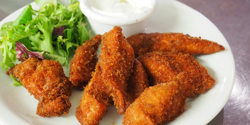 A close-up view of fritters served on a plate accompanied by a dip and lettuce leaves
