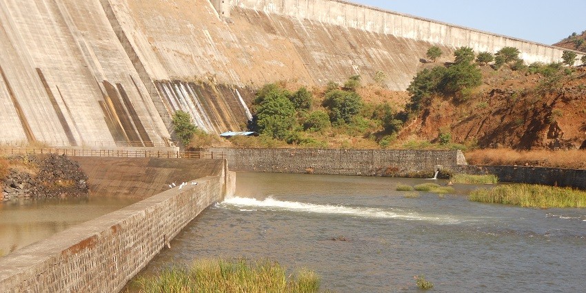 View of Temghar Dam with a wide concrete structure, surrounded by green hills and trees