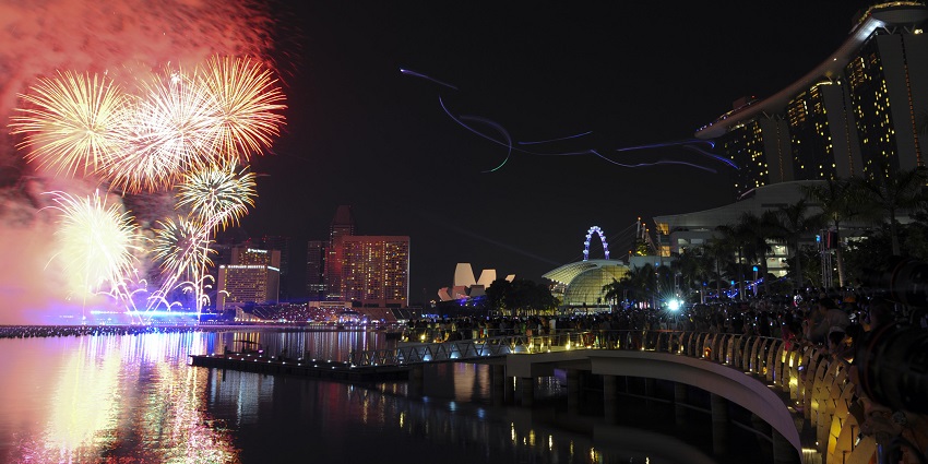 An array of fireworks display on the streets casting a refelecton on the serene waters.