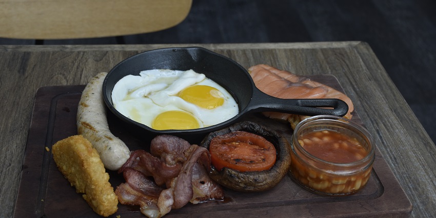 An English breakfast tray consisting of eggs, bacon, baked beans, tomato, and sausages, one of the famous food in Nagpur.