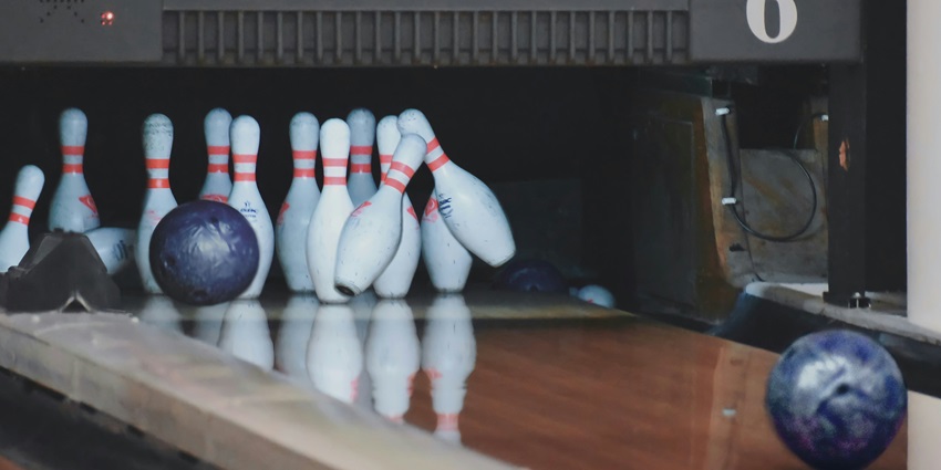 An incredible focused shot of a bowling alley with a bowling ball and bowling pins.