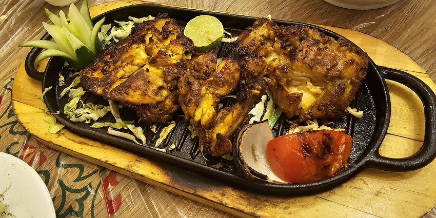 Grilled Chicken Tikka served on a sizzling plate with assorted vegetables and Lemon wedge