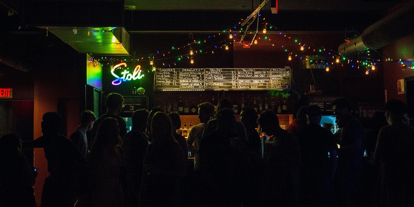 People around the bar table in the club adorned with warm lights