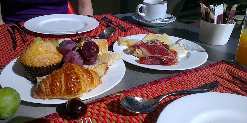 A spread of Continental breakfast, inclusive of croissants, fruits, meat, and cheese.