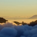 A scenic view of Mount Gunung Agung surrounded by clouds during a sunset, one of the things to do in Bali.