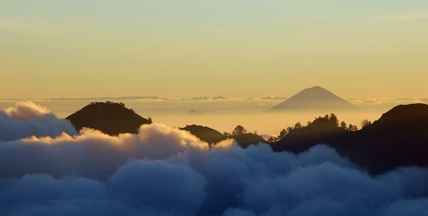 A scenic view of Mount Gunung Agung surrounded by clouds during a sunset, one of the things to do in Bali.