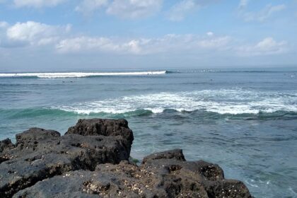 The beautiful view of Canggu beach with trees around and waves hitting the shore.