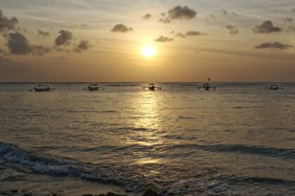 The beautiful sunset picture with boats on the water in Kuta, Bali, Indonesia.