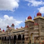 Mysore Palace in the morning, with golden domes and arches, surrounded by greenery and clear skies.