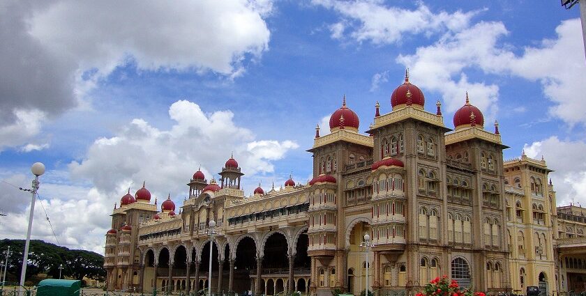 Mysore Palace in the morning, with golden domes and arches, surrounded by greenery and clear skies.