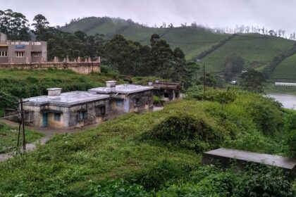 An image of a scenic Megamalai, featuring lush green mountains and quaint houses.