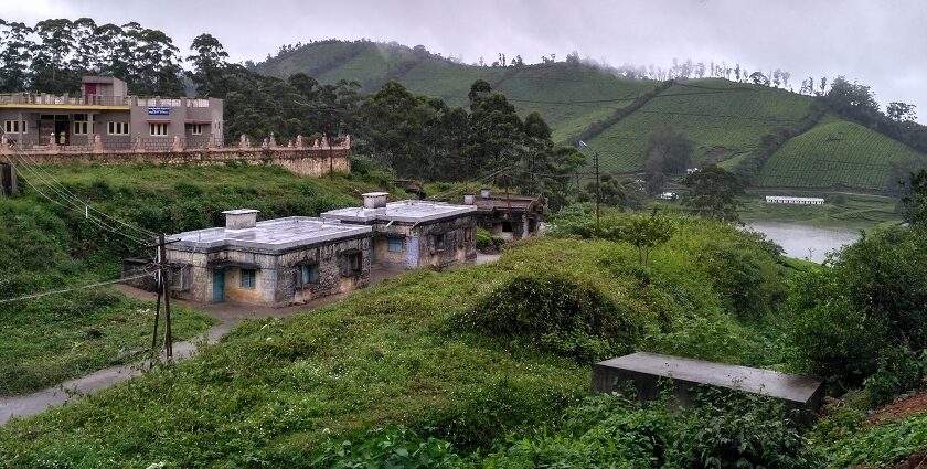 An image of a scenic Megamalai, featuring lush green mountains and quaint houses.