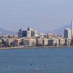 Panoramic view of Mumbai's skyline along Marine Drive against a sunset.