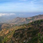 A breathtaking vista of green-capped mountains surrounded by lush green vegetation.