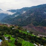 A glimpse of majestic peaks dotted with lush green vegetation and colourful houses.