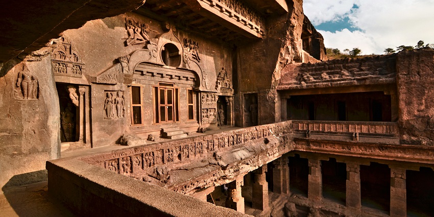 A grey temple design with multiple floors and balconies, under a cloudy sky in Tamil Nadu.