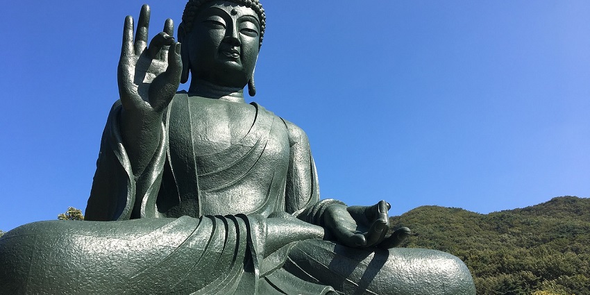 Buddha statue against a blue sky, representing a famous temple in Tamil Nadu.