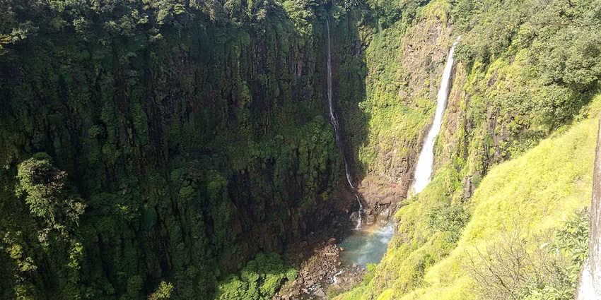 Majestic cascading waterfalls surrounded by lush green scenic beauty.