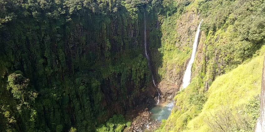 View of the water cascading down the large and lushious cliff