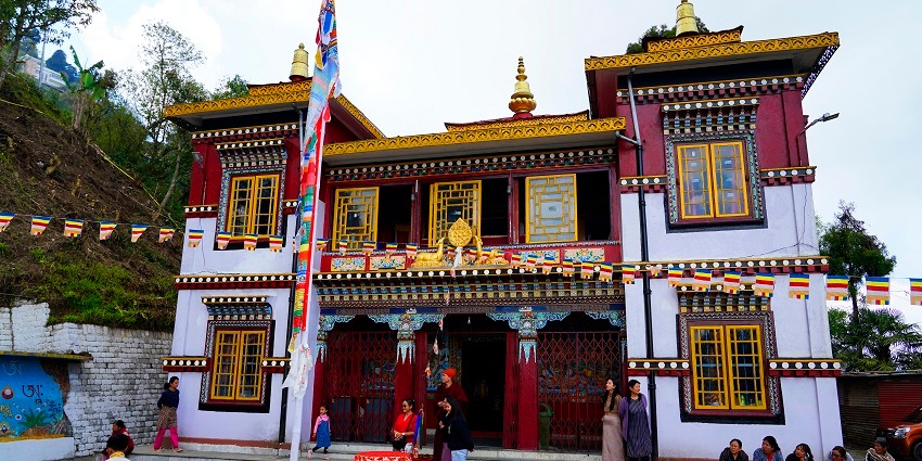 The entrance of the Tibetan Karma Temple and Monastery with people walking around.