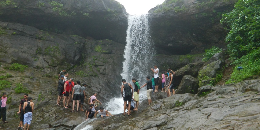 Waterfall at the Tiger Point in between two rocky hills crowded with tourists for kayaking in Lonavala.