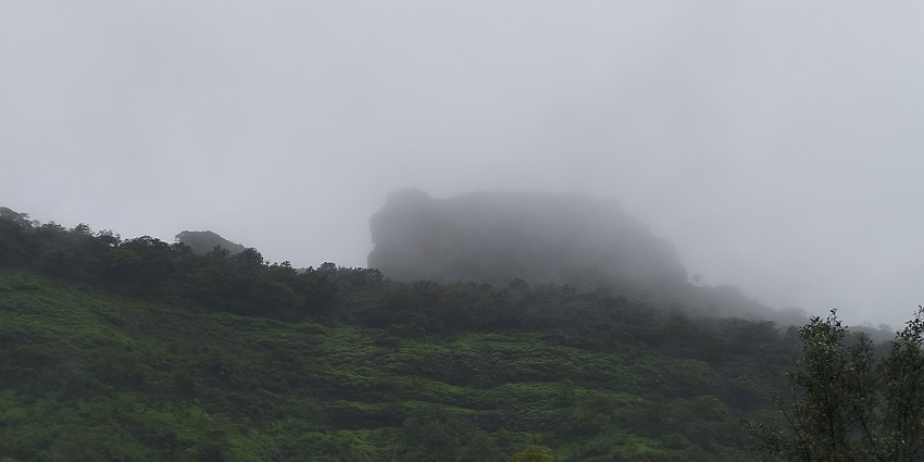 A view of entrance of Fort Tikona, surrounded by green hills during the rainy season
