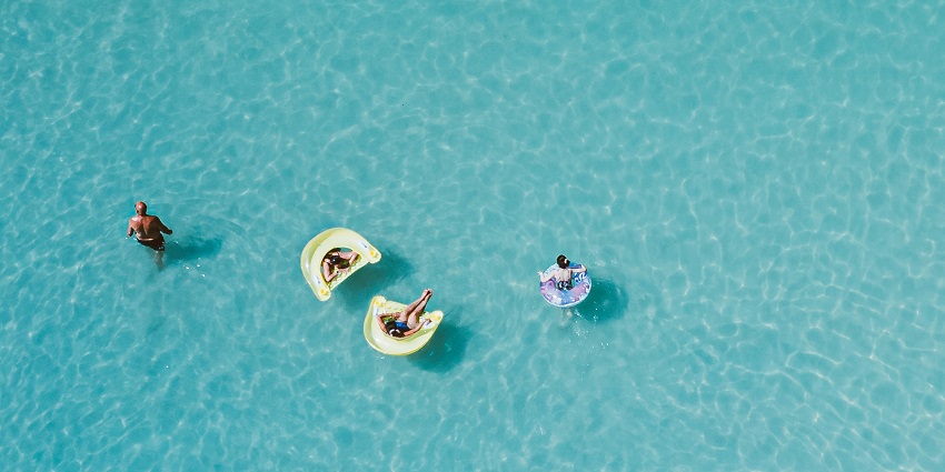 A view of a child relaxing on a pink inflatable in a clear swimming pool near Maharashtra.