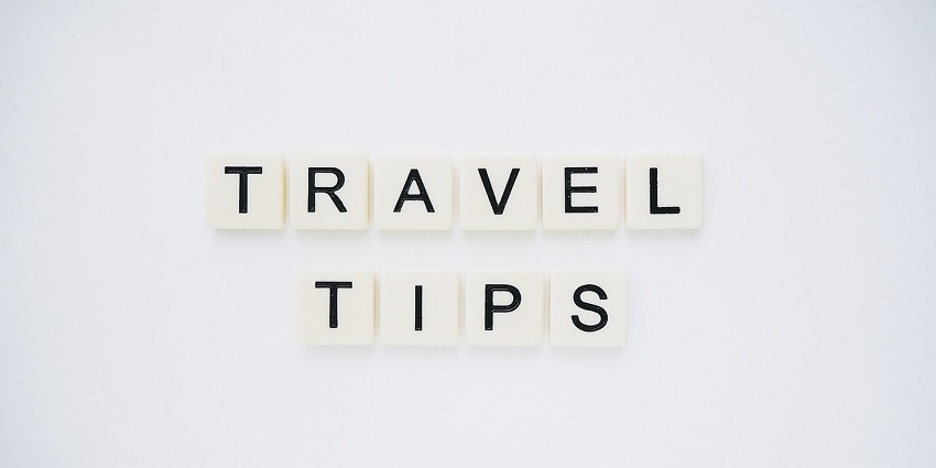 A frontal view of a white plain surface with white and black scrabbles saying travel tips.
