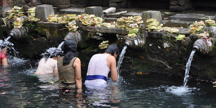 Devotees taking a purifying bath at a pool in Tirta Empul Temple, one of the best places to visit in Ubud.