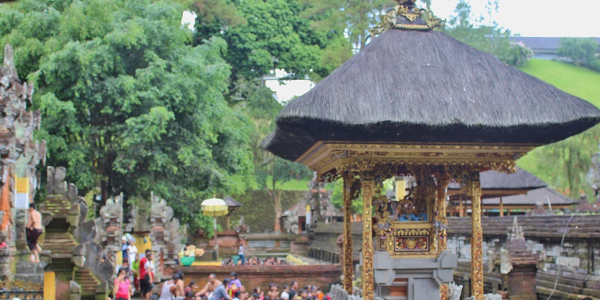 Panoramic view of Tirta Empul Temple in Bali with people taking a dip in the holy water.