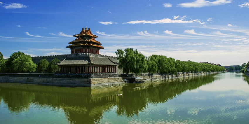 A picture of Tirta Gangga with tiered roofs situated near a calm body of water.