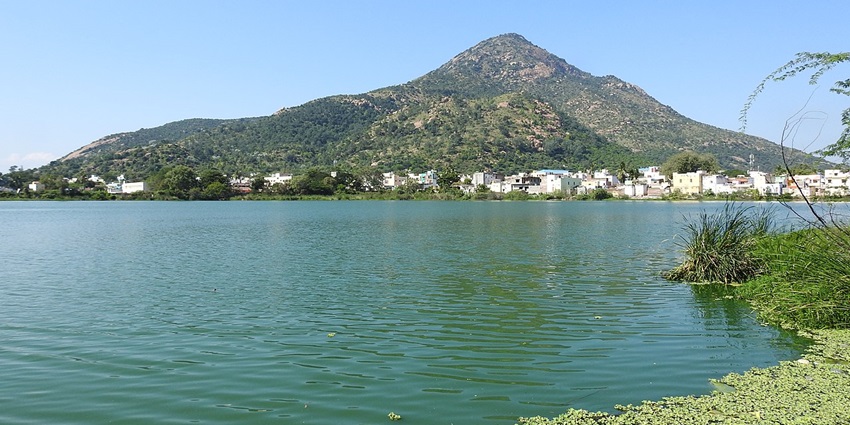 An incredible view of a pristine lake surrounded by lush green hills in Thiruvannamalai.