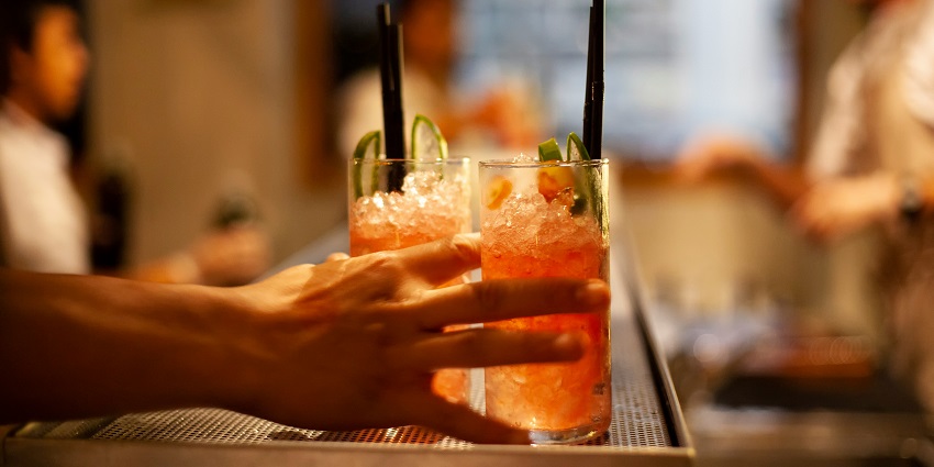 Image of a close up view two drinks in peach colour with ice served on a tray