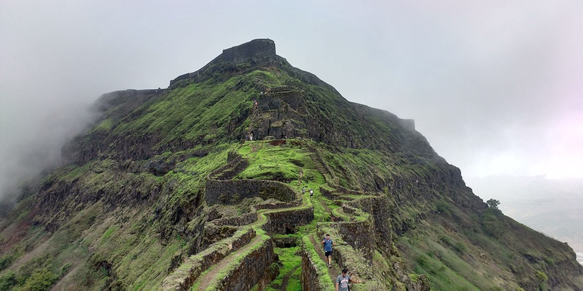 A view of Torna Fort, with lush green surroundings and uniquely designed pathways.