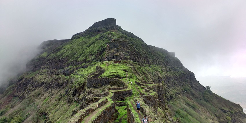 The entrance of Torna Fort, features ancient stone structures and scenic views.