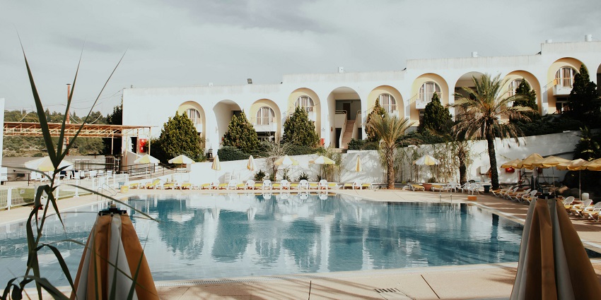 A resort which offers large bed, modern decor, and a window offering a city skyline view.