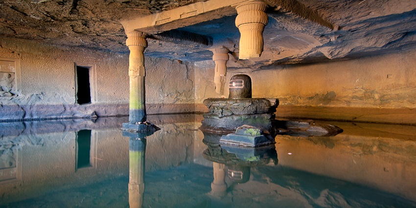 Rock-cut Kedareshwar shrine carved into stone amidst greenery–things to do in bhandardara