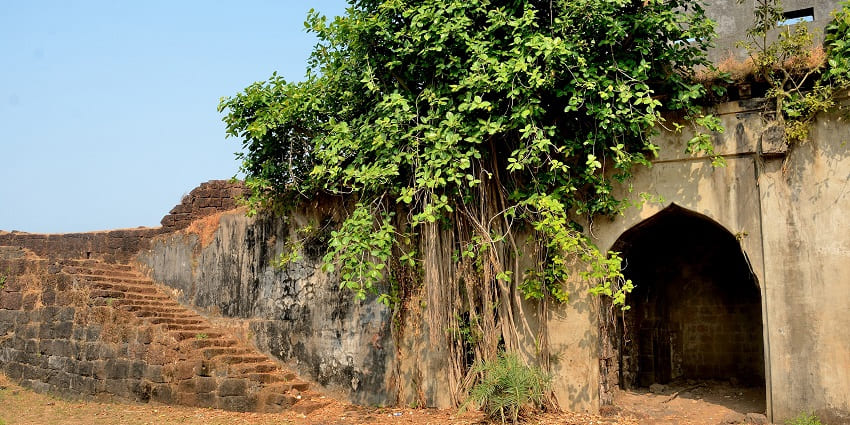 A glimpse of the rustic Kanakdurg Fort surrounded by lush greenery in Maharashtra.