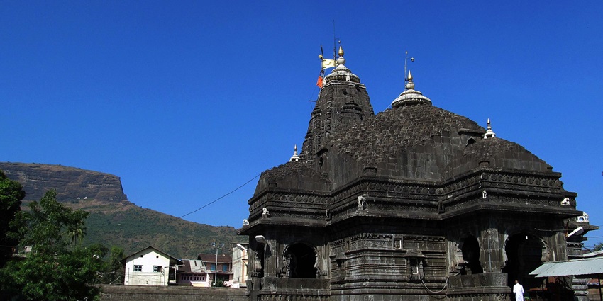 A picture of a temple taken from a distance with a mountain in the background