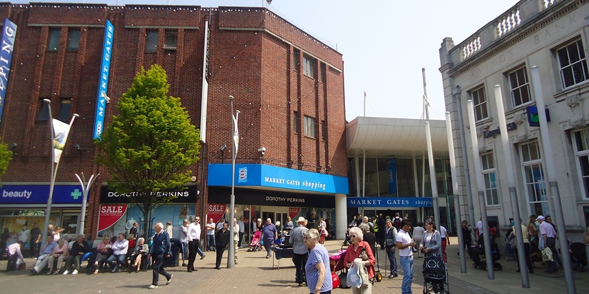 A picture of a shopping street showing wanders, sellers and visitors all around.