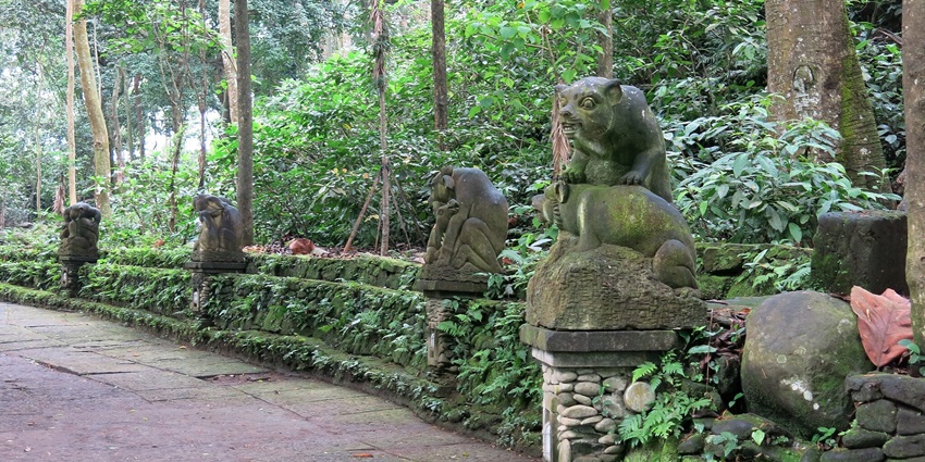 A concrete path with stone statues of monkeys in the Sacred Monkey Forest in Ubud.