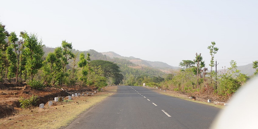 A rural highway in Maharashtra, India, with a wide, paved road surrounded by greenery.