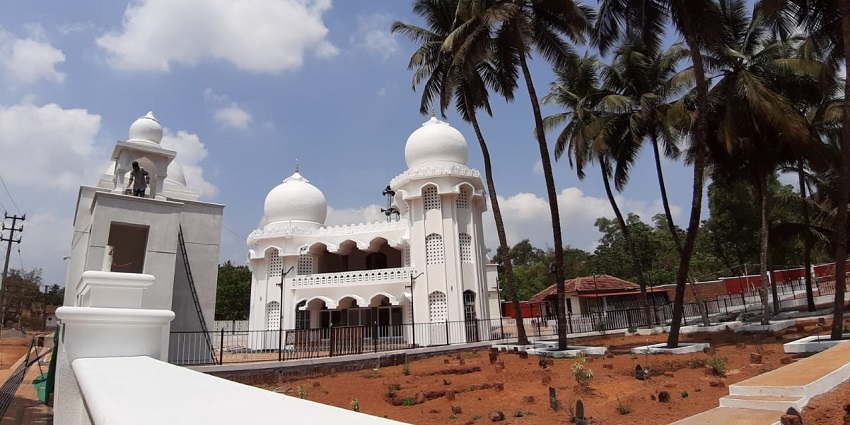 A picture of a mosque with white walls and green surroundings