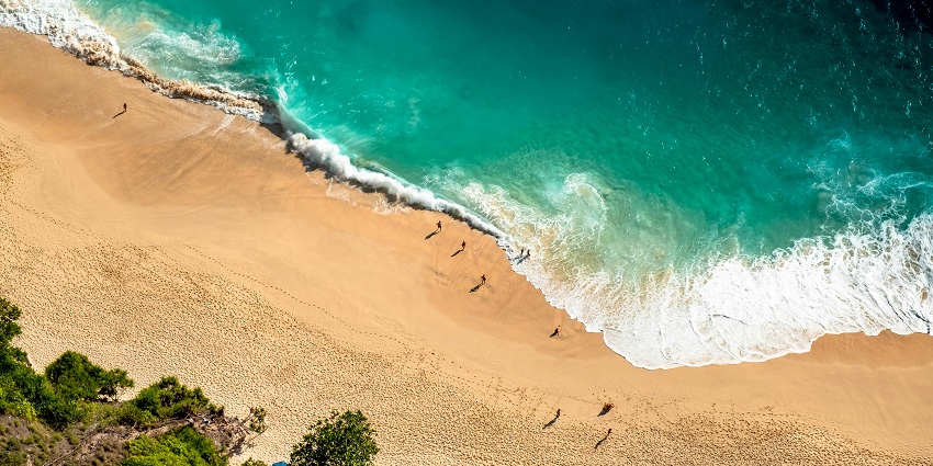 An aerial view of Padang Padang Beach beach on which people are present