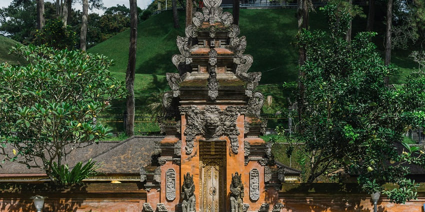 An image of Uluwatu Temple perched on a cliff overlooking the Indian Ocean at sunset.