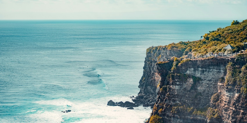 An image of Uluwatu Temple perched on a cliff with a sunset view over the ocean.
