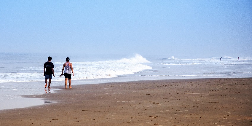 Two people walking the shores of utorda beach in the morning